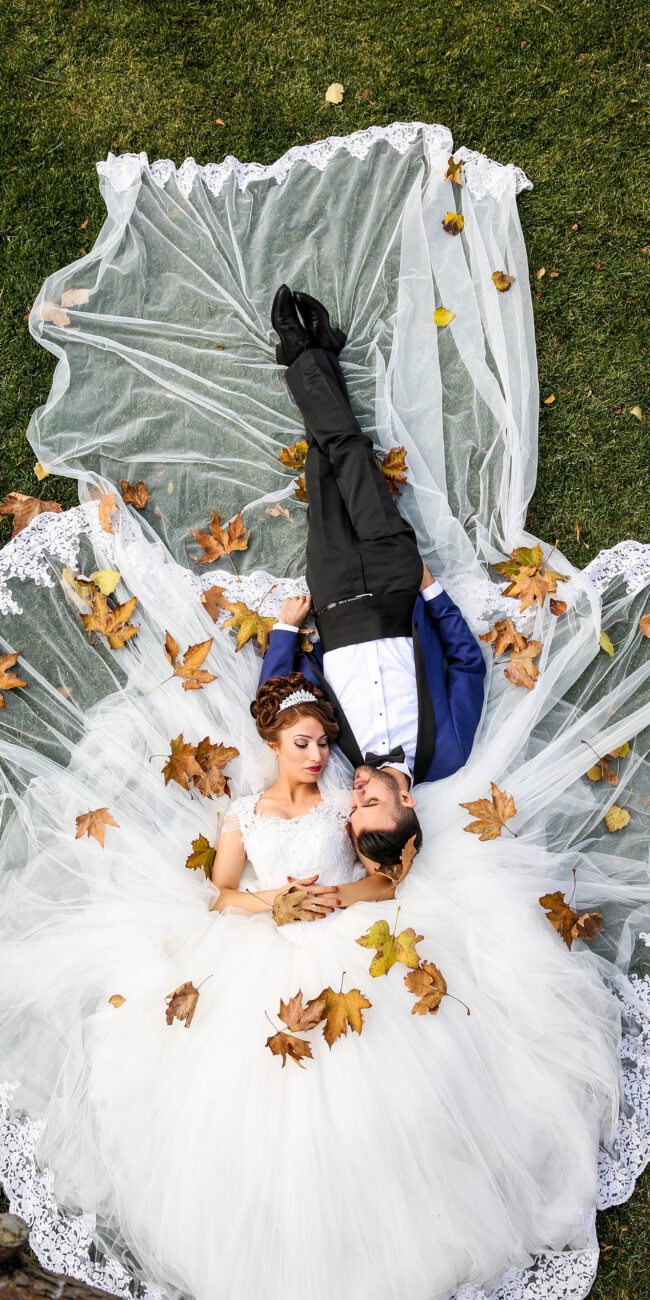 Brautpaar liegend auf einer Wiese - Herbstblätter